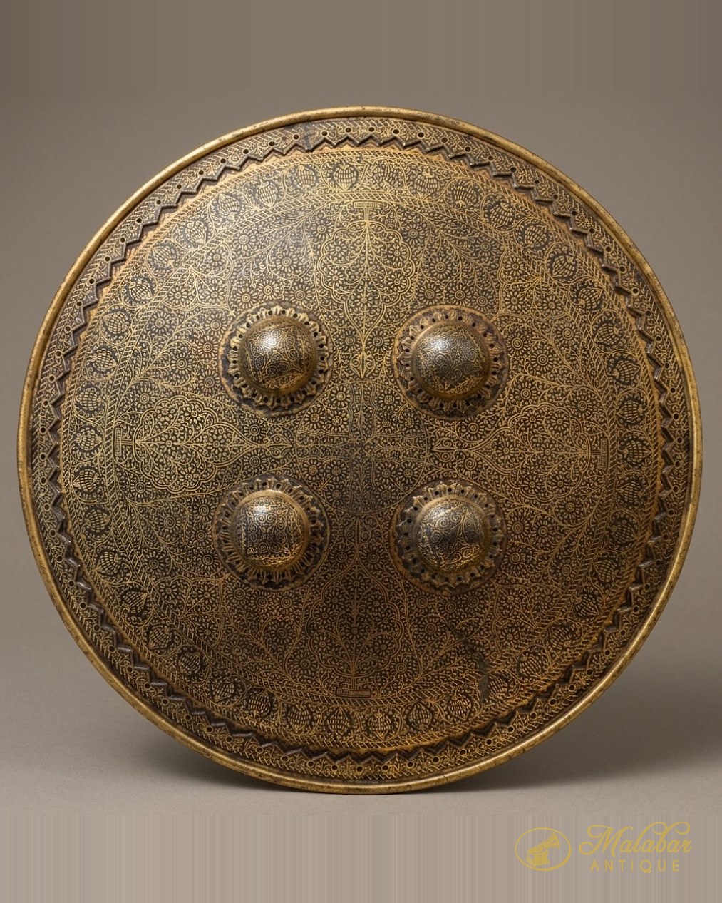 Large brass shield engraved overall and set with four raised bosses.