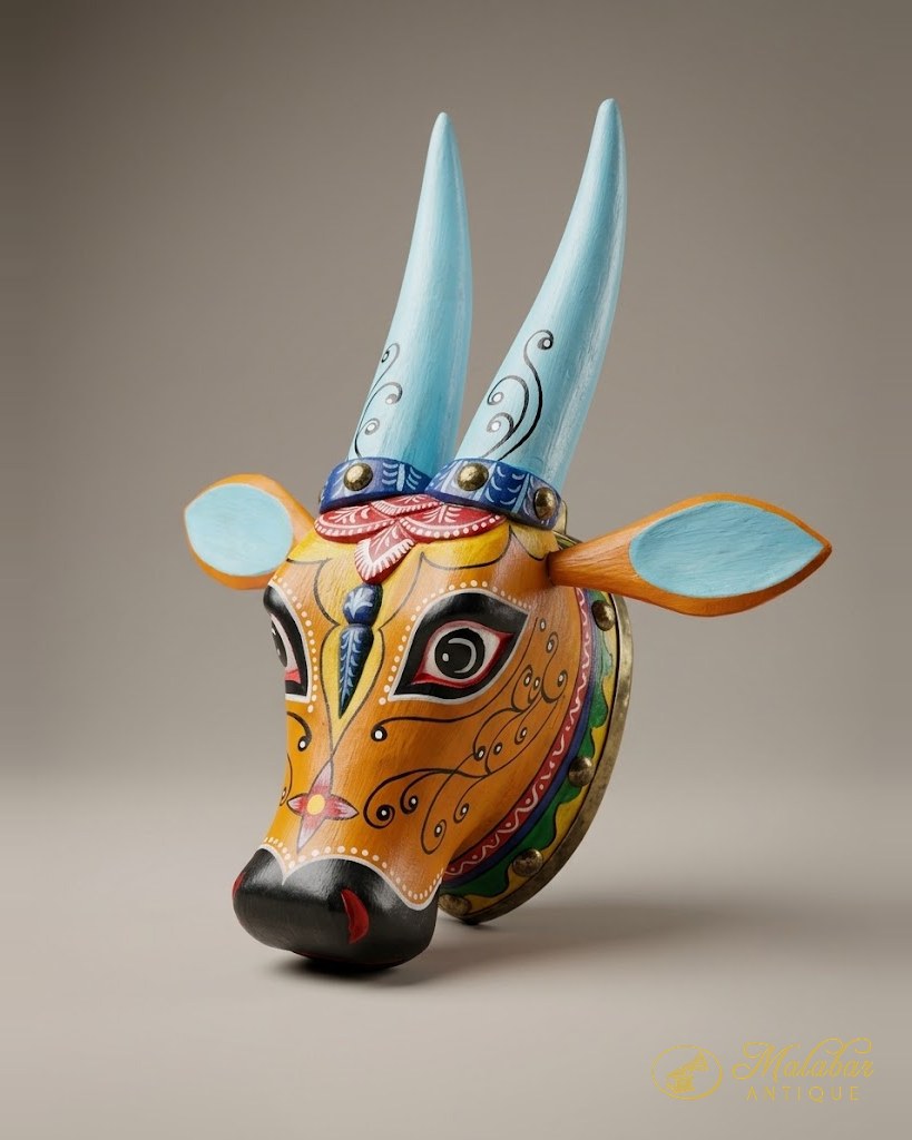 Brightly painted wooden cow mask with pale blue horns and ears, black muzzle and red, yellow and green scrollwork over the face.