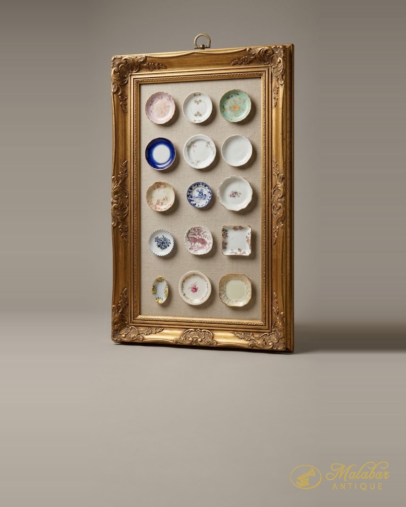 Ornate gilt frame with a linen ground displaying fifteen miniature porcelain plates and saucers in mixed floral and transfer patterns.