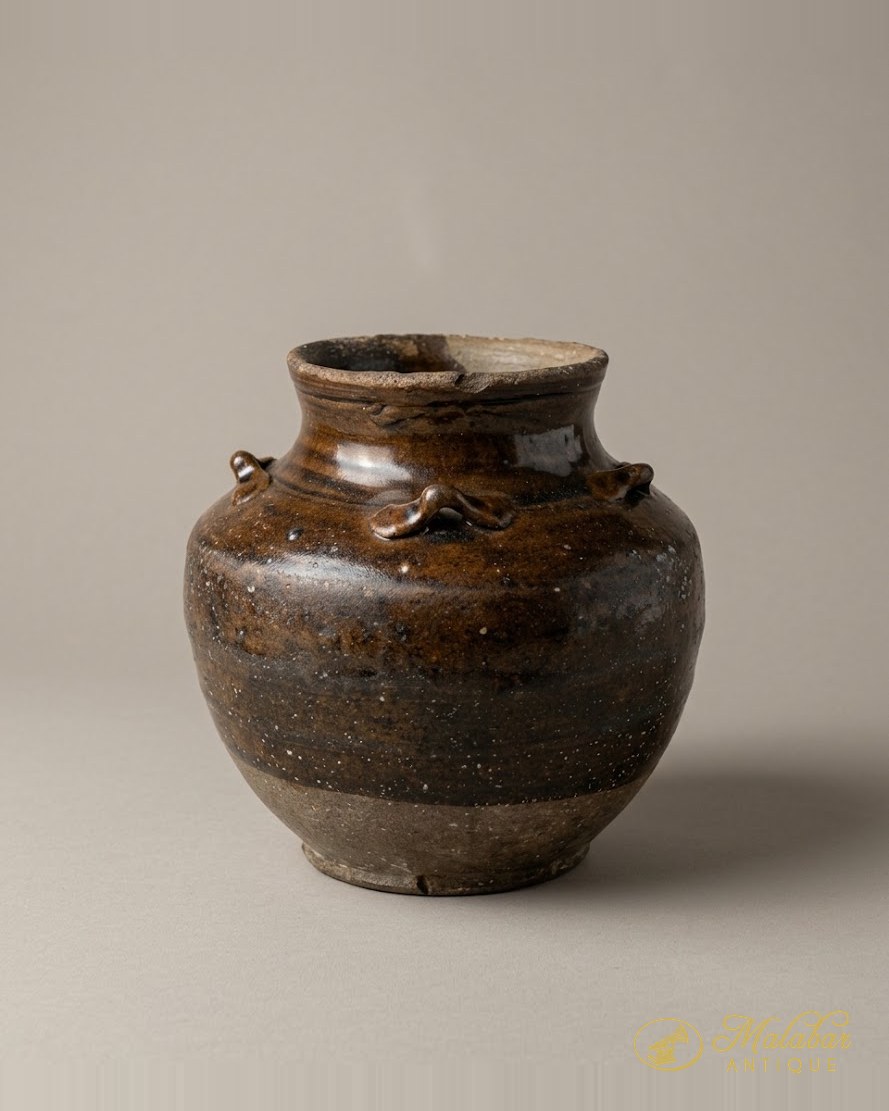 Small lug-handled storage jar in a mottled treacle-brown glaze stopping short of an unglazed buff foot.