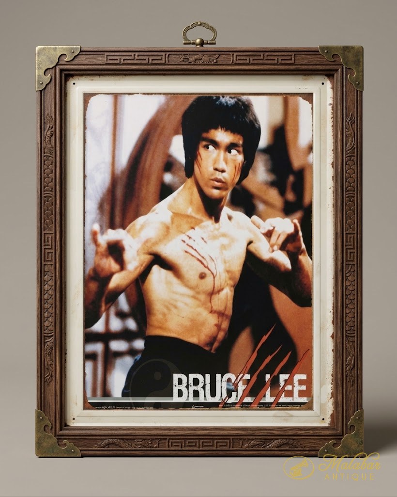 Framed tin film poster of Bruce Lee in a fighting stance, in a carved wooden frame with brass corner mounts.