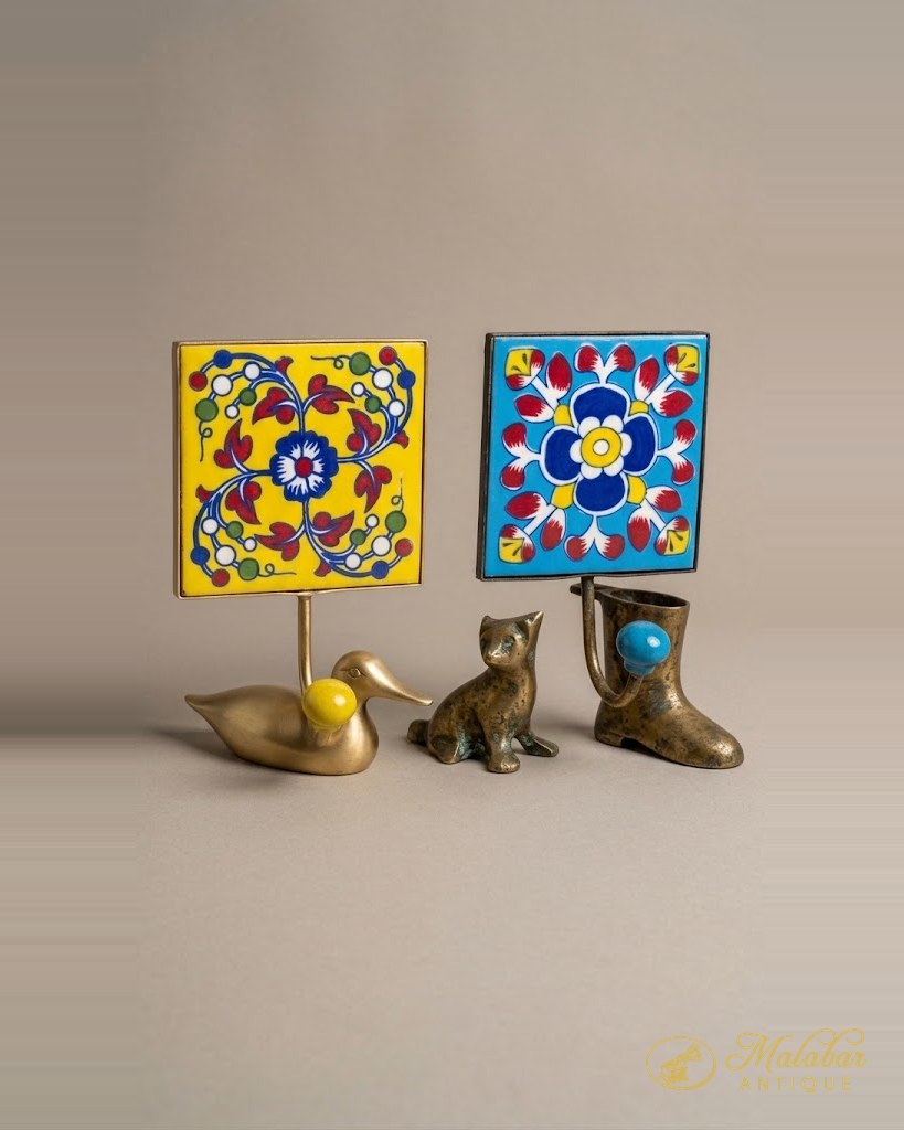 Two painted tile plaques with small brass animal figures.