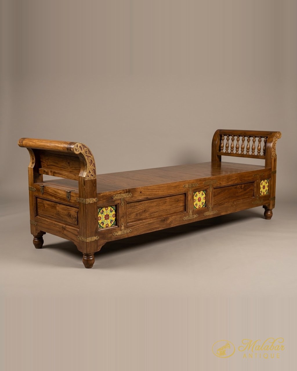 Long teak daybed with scrolled ends, turned spindle back, brass strapping and inset yellow and red painted tiles.