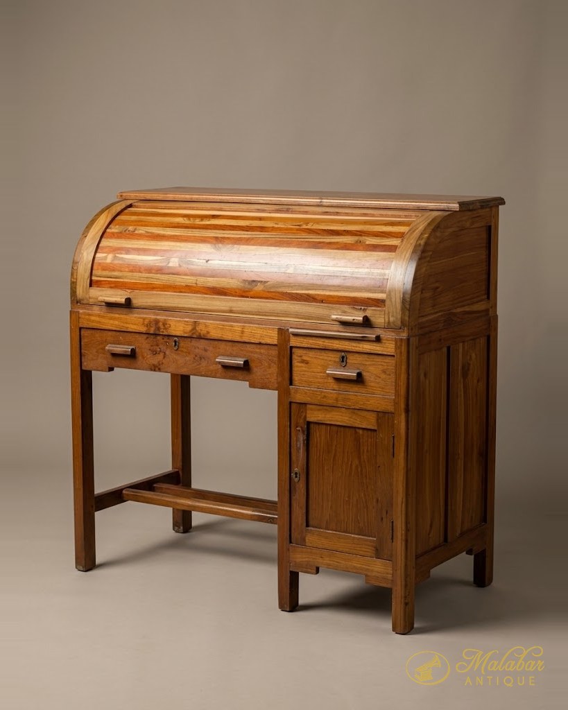 Teak roll-top writing desk with a tambour shutter, three drawers, a panelled cupboard and a stretcher footrest.