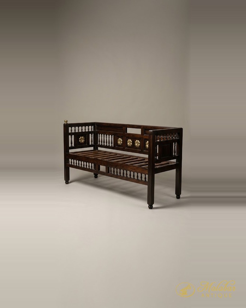 Dark rosewood settee with turned spindle gallery, brass rosette bosses and a slatted seat frame.