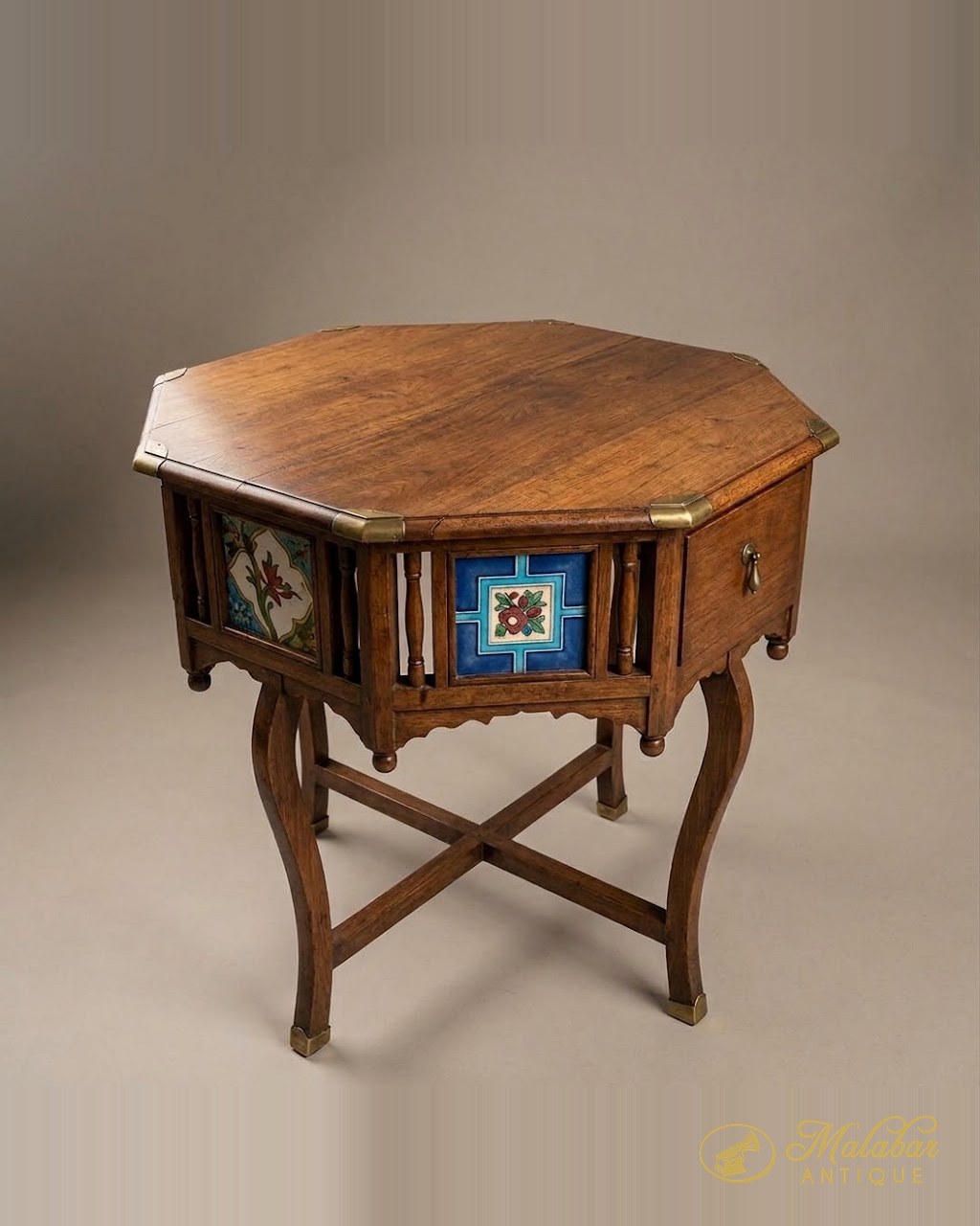 Octagonal teak table with painted tile panels and cabriole legs on a cross stretcher.