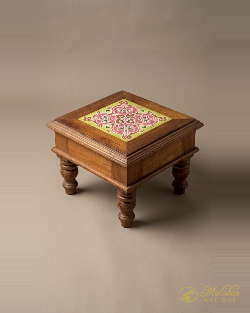 Low teak stool with a painted floral tile set into the top and turned legs.