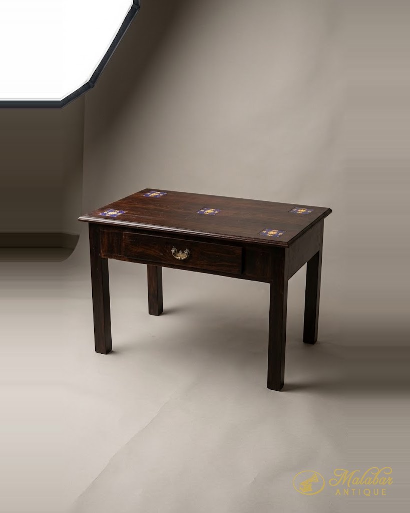 Small writing table with a single drawer and inset tiles to the top.