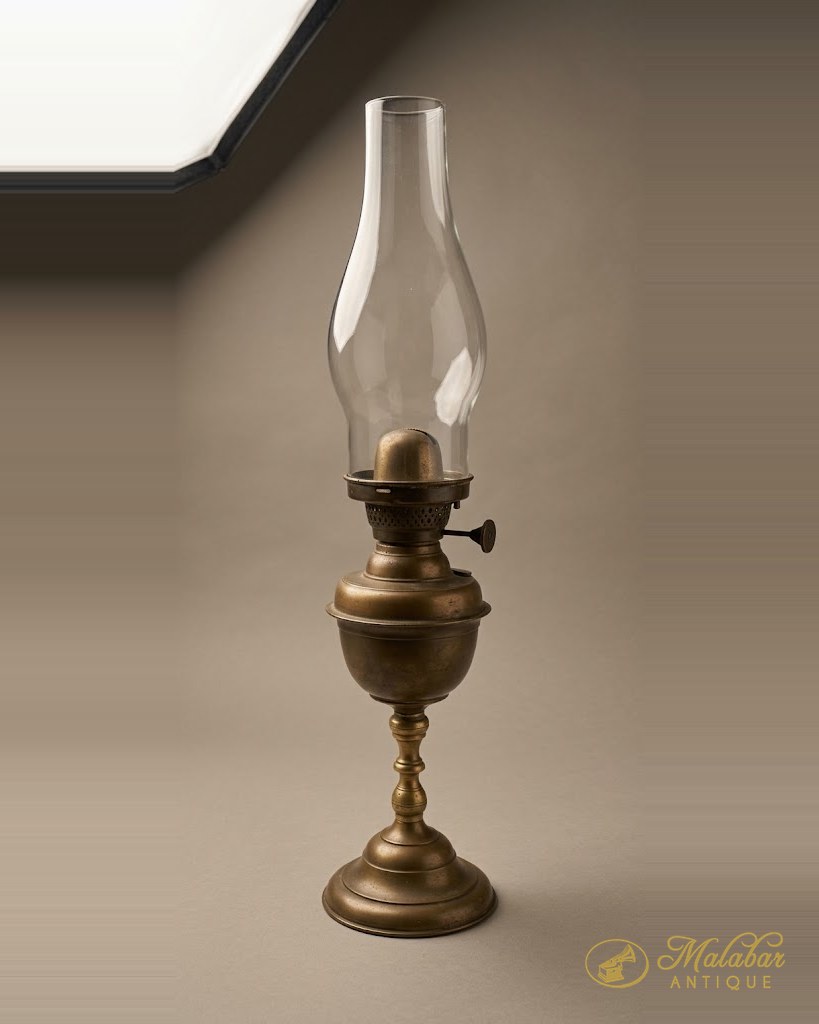 Brass oil lamp with a baluster stem and a tall clear glass chimney.