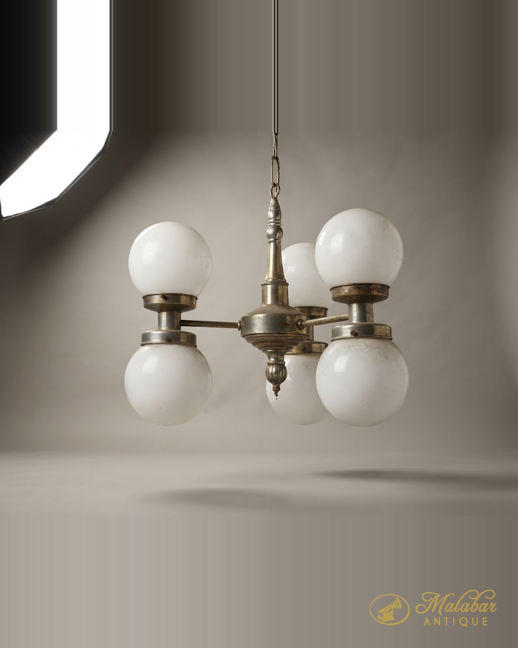 Four-arm brass chandelier hung with white opal glass globes.