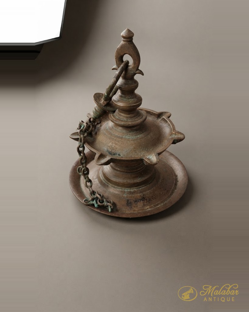 Thooku vilakku — a hanging brass oil lamp with a petalled bowl and suspension chain.