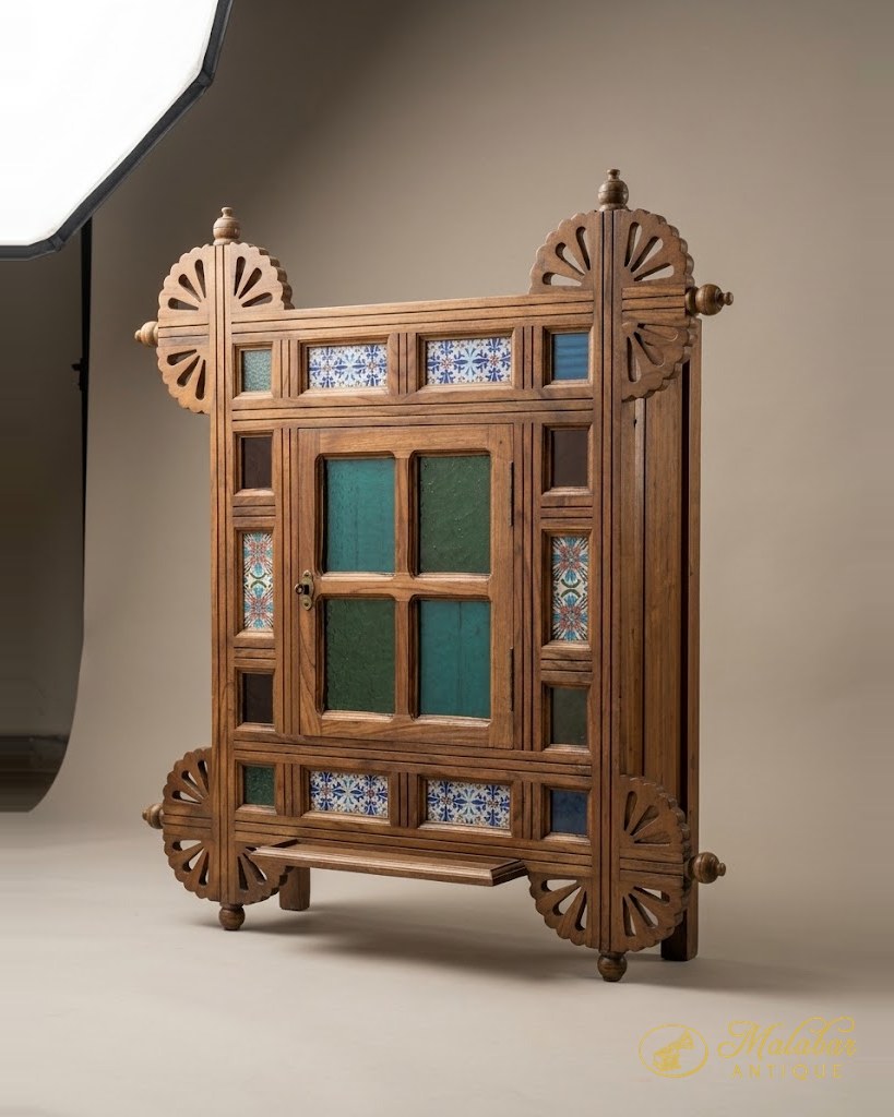 Teak window frame with fan-carved roundels at the corners, turned finials, green glazed panes and borders of blue and white patterned tiles.