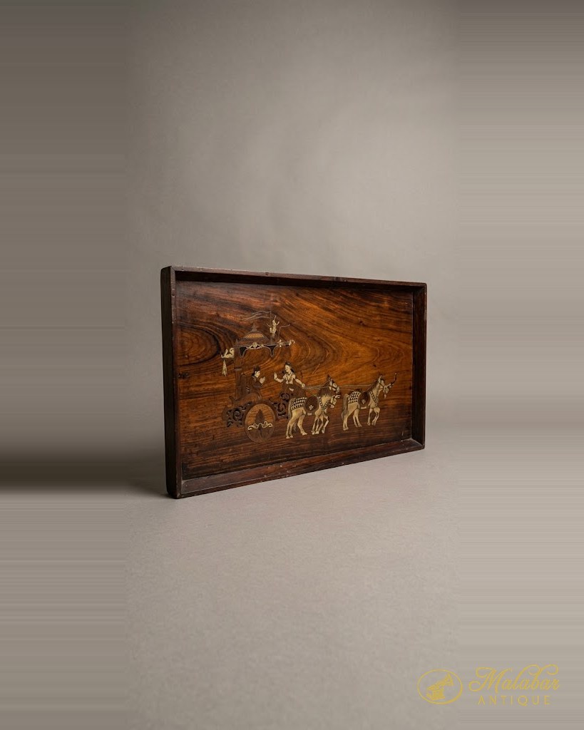 Rosewood panel inlaid in brass with a procession of figures.