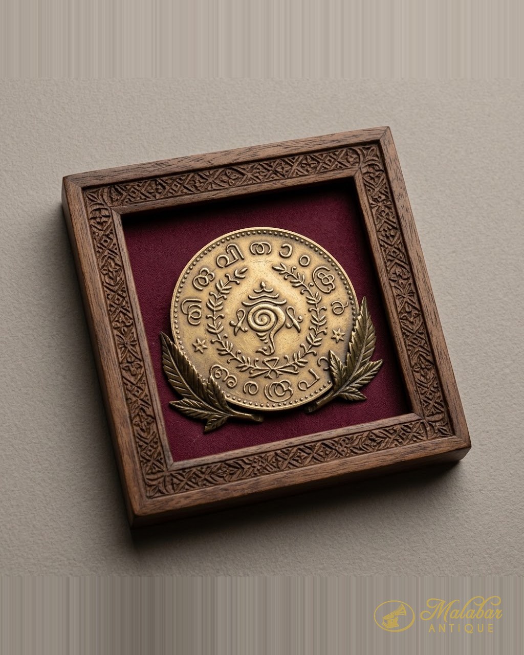 Brass medallion with Malayalam lettering, mounted on velvet in a carved wooden frame.